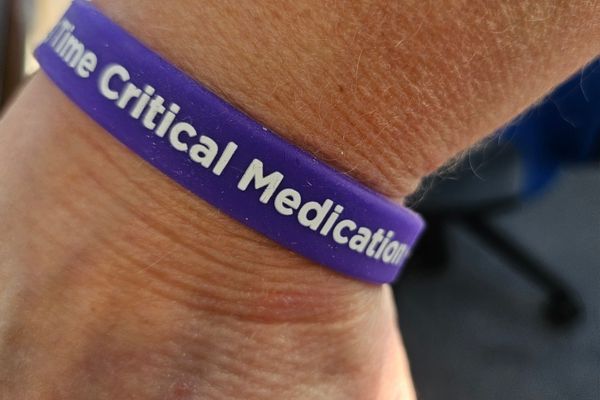 A purple wrist band that says "Time critical medication".