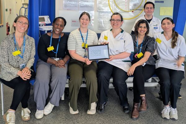 A group of staff sitting on a bench and holding the new tablet.