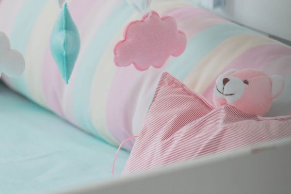 A colourful cot with a pink teddy.