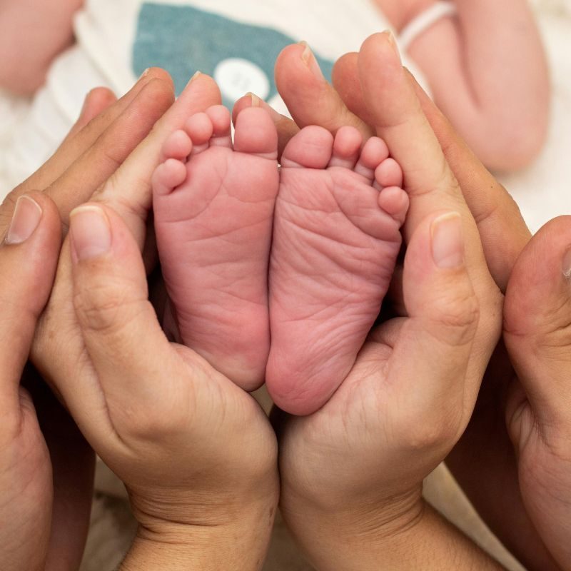 Parents holding their baby's feet in their hands.